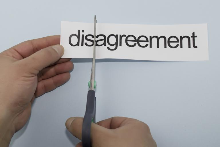 The word disagreement being cut with a pair of scissors from a document