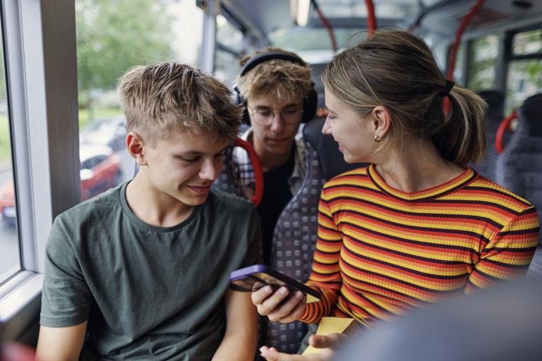 Teenagers talking and using their mobile phones on a bus
