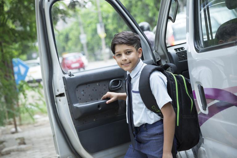 Young Indian pupil getting our of a car